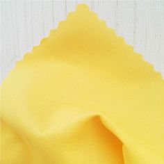 yellow fabric with scalloped edges on white wooden background, closeup view photo