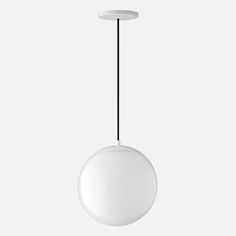 a white round light hanging from a black cord on a gray background with an object in the foreground