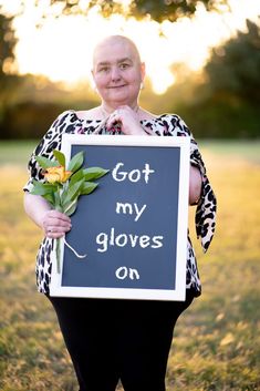 a woman holding a sign that says got my gloves on with flowers in front of her