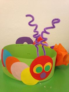 a colorful paper bowl sitting on top of a green table next to some purple and orange streamers