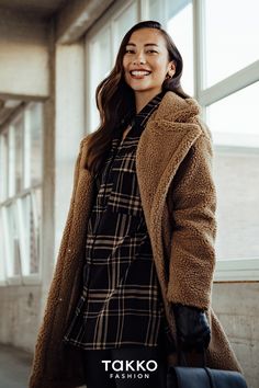 Looks mit Teddyfell sind in der Damenmode voll im Trend. Im Herbst und Winter hält ein Teddymantel oder eine Teddyjacke Dich schön warm. Der kuschelige Stoff ist besonders in Beige oder Braun sehr modisch. Der Mantel aus Teddyfell in Beige hat außerdem einen hübschen Kragen und praktische Taschen. Zum großen Mantel in Oversize stylen wir eine enge schwarze Hose. Das Karohemd mit Karos in Braun passt gut zur Jacke. Der schwarze Rucksack ist ein modisches Accessoire. Beige Hat