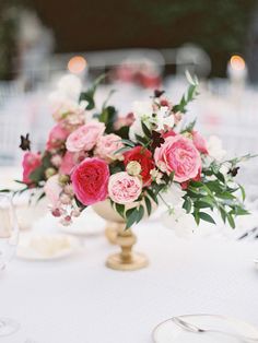 a vase filled with pink and white flowers sitting on top of a dining room table