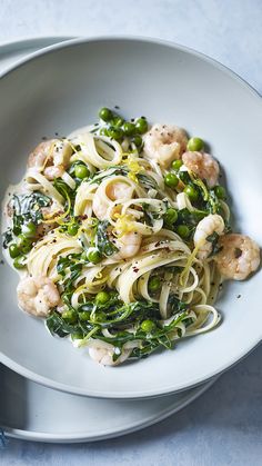 pasta with shrimp, broccoli and spinach in a white bowl on a blue surface