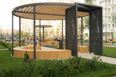 a gazebo in the middle of a park with people sitting and walking around it