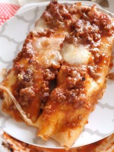 a white plate topped with lasagna covered in sauce