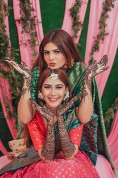 two women sitting on top of each other with their hands covered in hendi tattoos