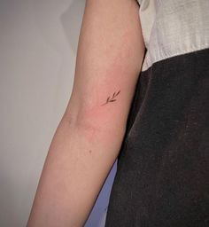 a woman's arm with a small arrow tattoo on the left side of her arm