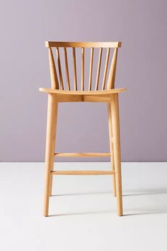 a wooden chair sitting on top of a white floor next to a purple wall in front of it