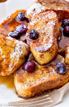 french toast topped with blueberries and powdered sugar on a white plate next to a fork