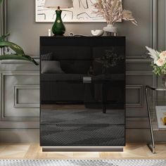 a living room with a black cabinet and white flowers in vases on the table