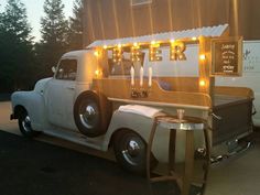 an old truck is parked in front of a building with lights on it's side