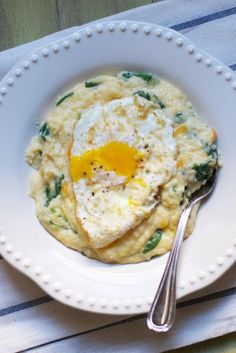 a white plate topped with an egg on top of mashed potatoes