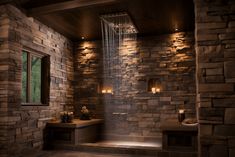 a bathroom with stone walls and lights in the shower head is lit by two candles