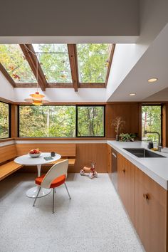 a kitchen with a table and chairs in front of a window that looks out onto the woods