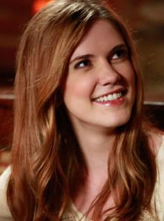 a woman sitting at a table with a plate of food in front of her smiling