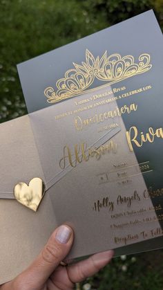 a person holding up a wedding card with a gold heart on the front and back