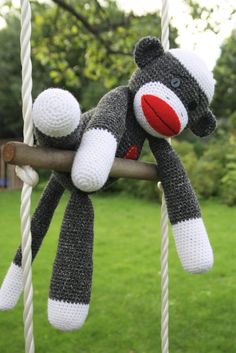 a crocheted sock monkey hanging from a swing