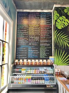 the menu is displayed on the blackboard behind the deli counter with drinks and condiments