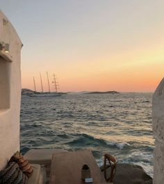 the sun is setting over the ocean with boats in the distance