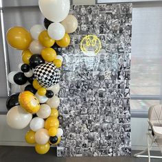 a bunch of balloons hanging from the side of a wall next to a chair and table