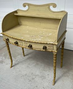 an old desk with two drawers on the top and one drawer open, sitting in front of a garage door