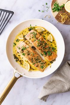 a white bowl filled with fish and lemons on top of a marble countertop