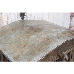 an old wooden table with peeling paint on the top and bottom surface, in front of a brick wall