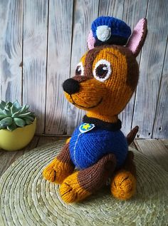 a knitted dog sitting on top of a wooden table next to a succulent plant