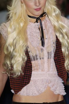 a woman with long blonde hair wearing a black and white outfit on the catwalk