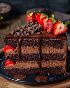 a piece of chocolate cake with strawberries and chocolate frosting on a black plate