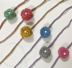 four crocheted flower beads are shown on a white surface with multicolored thread