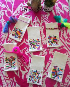 several pieces of embroidered fabric are laid out on a pink tablecloth with cactuses