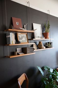 some shelves with books and plants on them against a wall in a living room or dining room