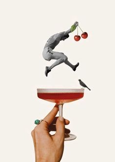 a person holding a wine glass in the air with two birds on top of it