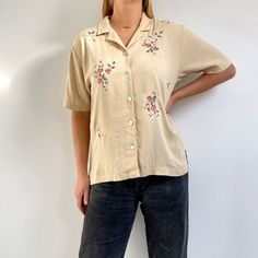 Beautiful 90's white blouse decorated with satin ribbon and embroidery. It has short sleeves, straight shape, side slits, neat collar and small pearlescent buttons. Made from a lightweight, crinkled fabric. Perfect blouse for summer. Made in Mexico by Teddi. 40% polyester, 40% rayon, 20% flax/linen. Medium size. Measurements when laid flat are: Pit to pit: 54cm Waist: 52cm Length: 64cm. Excellent condition. E Beige Embroidered Button-up Top, Cream Collared Embroidered Top, Cream Embroidered Collared Top, Embroidered Cream Button-up Top, Embroidered Short Sleeve Daywear Shirt, Embroidered Short Sleeve Day Shirt, Cream Embroidered Short Sleeve Blouse, Embroidered Short Sleeve Shirt For Daywear, Vintage Floral Embroidered Short Sleeve Shirt