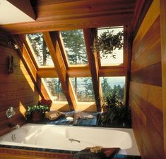 a bath tub sitting inside of a bathroom next to a wooden wall and window sill