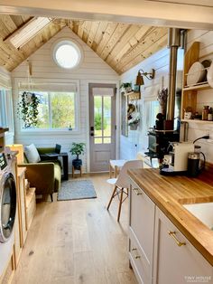 an open kitchen and living room area in a tiny home with wood floors, white walls, and ceiling beams