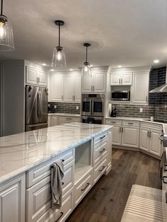 a large kitchen with white cabinets and marble counter tops, along with stainless steel appliances