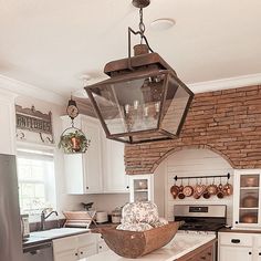 a kitchen with white cabinets and an old fashioned light fixture hanging from the ceiling over the island