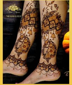 the legs and feet of a woman with henna tattoos on their ankles, decorated with gold