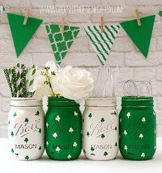 four green mason jars with white flowers in them