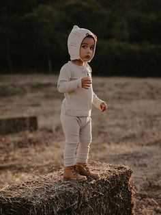 a small child standing on top of hay bales