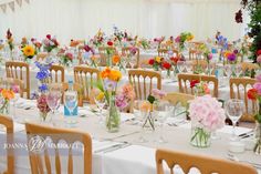 the tables are set up with flowers in vases and glassware on each table