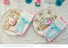 two plates with cupcakes on them are sitting on a lace tablecloth next to pink and blue napkins