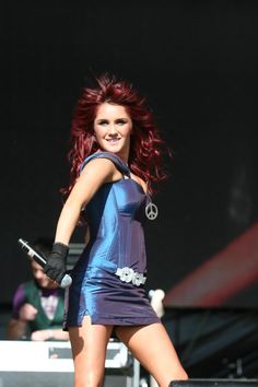 a woman with red hair and black gloves is performing at a music festival on stage