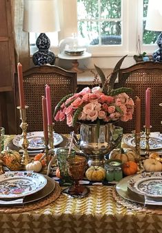 a dining room table set with plates and candles