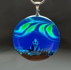 We love watching the magnetic dance of the northern lights. It's a great feeling to reflect this on our necklaces. We placed a three-dimensional tiny panda inside, completely hand-painted. I can customize this necklace for you. The pendant is combined with a piece of exotic wood and resin. This necklace is a great gift for those who love the aurora borealis. The necklace has an excellent shine. The necklace is absolutely unique and it is impossible to make a new piece exactly like it. This will Luminous Spiritual Jewelry As A Gift, Luminous Spiritual Jewelry For Gifts, Spiritual Luminous Jewelry As Gift, Luminous Pendant Necklace For Gift, Magical Round Pendant Necklace As Gift, Magical Round Pendant Necklace For Gift, Unique Luminous Jewelry As A Gift, Unique Luminous Jewelry For Gifts, Tiny Panda