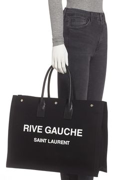 Perfect for days when you're toting a lot but still want to look Left Bank-chic, this spacious canvas tote features rolled leather handles and a bold logo. Style Name:Saint Laurent Noe Rive Gauche Logo Canvas Tote. Style Number: 6084311. Designer Canvas Bag With Large Capacity For Everyday, Designer Large Capacity Canvas Bag For Everyday, Chic Canvas Bags With Logo, Chic Canvas Shoulder Bag With Logo, Black Cotton Shoulder Bag With Logo, Luxury Logo Canvas Bag For Everyday Use, Designer Canvas Shoulder Bag With Logo, Coated Canvas Bag With Logo For Shopping, Logo Coated Canvas Bag For Shopping