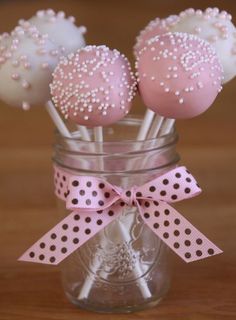 pink and white cake pops in a mason jar with polka dot ribbon on the top