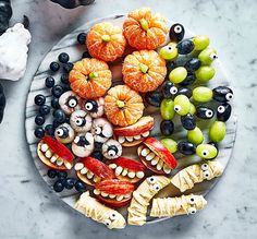 a plate filled with fruit and monster eyes on top of marble countertop next to halloween decorations